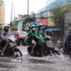Người dân di chuyển qua đoạn đường Đinh Bộ Lĩnh, phường Bình Thạnh bị ngập do cơn mưa chiều 23/9. (Ảnh: Hồng Đạt/TTXVN)