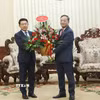 Đại sứ Việt Nam tại Lào Nguyễn Minh Tâm chuyển lẵng hoa chúc mừng của đồng chí Lê Minh Hưng, Ủy viên Bộ Chính trị, Thủ tướng Chính phủ Việt Nam chúc mừng đồng chí Saleumxay Kommasitt, Ủy viên Bộ Chính trị, Thủ tướng Chính phủ Lào. (Ảnh: Xuân Tú/TTXVN)