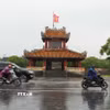 Các phương tiện di chuyển trong mưa lớn ở trước di tích Phu Văn Lâu, trung tâm thành phố Huế. (Ảnh: Nguyên Lý/TTXVN)