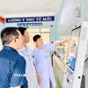 Cán bộ y tế hướng dẫn vận hành ki-ốt thông minh tại cơ sở y tế. (Ảnh: Quang Thái/TTXVN)