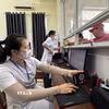 Nhân viên y tế quét mã lấy số và đăng ký khám bệnh tại các ki-ốt phát số tự động. (Ảnh: Đinh Hương/TTXVN)