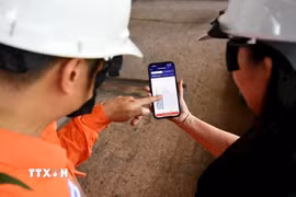 Công nhân (EVNHANOI) hướng dẫn khách hàng sử dụng Ứng dụng EVNHANOI trên website evnhanoi.vn. (Ảnh: Quốc Lũy/TTXVN)