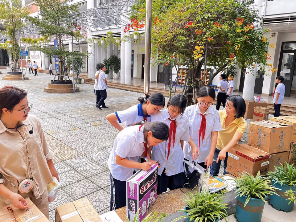 Các bạn học sinh phân loại, ghi lên từng thùng carton hàng hóa hỗ trợ. (Ảnh: PV/Vietnam++