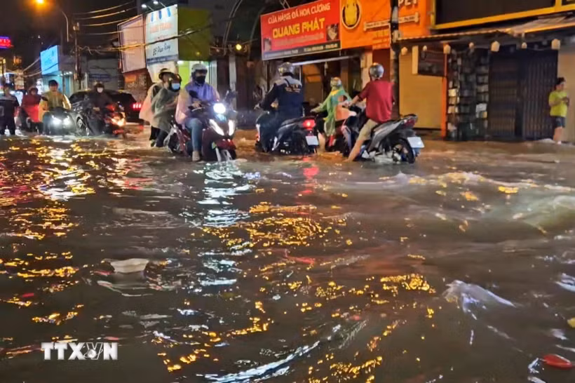 Người dân di chuyển trong điều kiện ngập nước do mưa lớn chiều tối ngày 1/10. (Ảnh: Hồng Đạt/TTXVN)