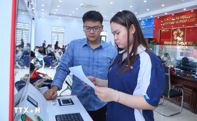 Cán bộ Trung tâm Phục vụ hành chính công xã Rạng Đông hướng dẫn người dân thực hiện thao tác tại Kiosk hành chính công. (Ảnh: Công Luật/TTXVN)