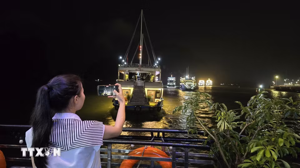 Du khách háo hức chiêm ngưỡng vẻ đẹp lung linh của Di sản thiên nhiên Thế giới vịnh Hạ Long về đêm. (Ảnh: Thanh Vân/TTXVN)