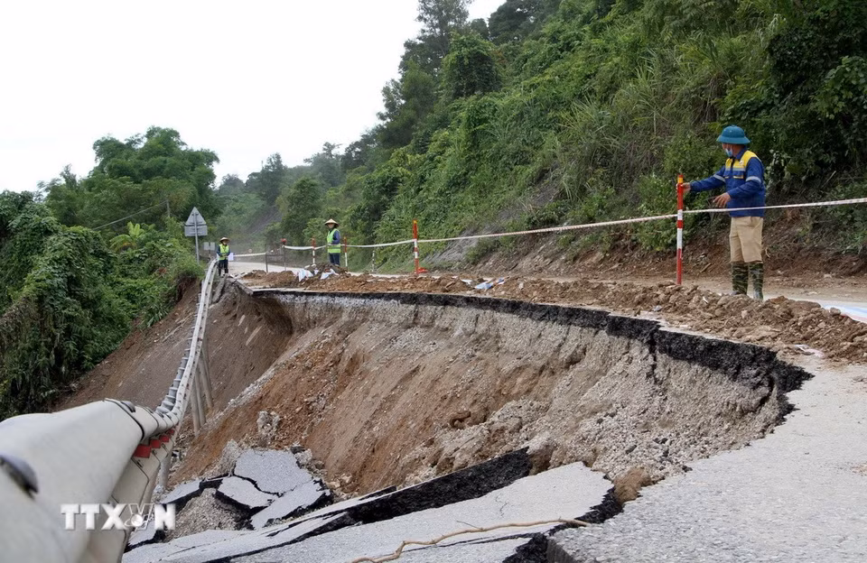 Lực lượng chức năng đã bố trí người cắm thiết bị cảnh bảo ở các điểm sạt lở cho các phương tiện giao thông đi qua. (Ảnh: Văn Tý/TTXVN)