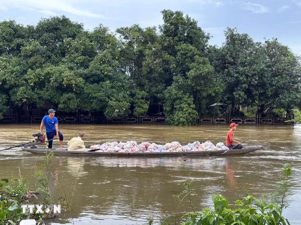 Các đoàn tình nguyện vận chuyển hàng hóa lên ghe để đưa vào những vùng ngập sâu ở thành phố Huế. (Ảnh: Đỗ Trưởng/TTXVN)