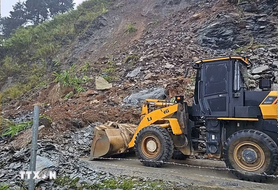 Máy xúc được huy động để san gạt đất đá để các phương tiện sớm được lưu thông. (Ảnh: TTXVN phát)