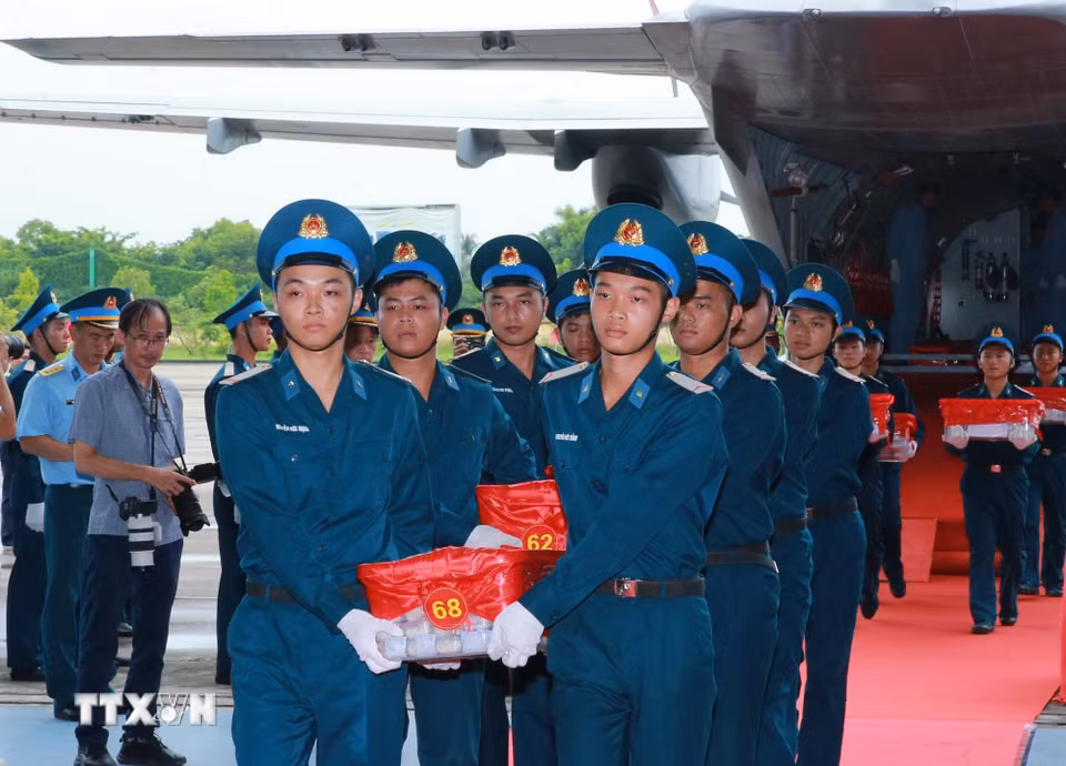 Nghi thức trang trọng chuyển mẫu hài cốt liệt sỹ từ máy bay xuống tại Sân bay Gia Lâm để làm lễ dâng hương tưởng niệm. (Ảnh: Trọng Đức/TTXVN)