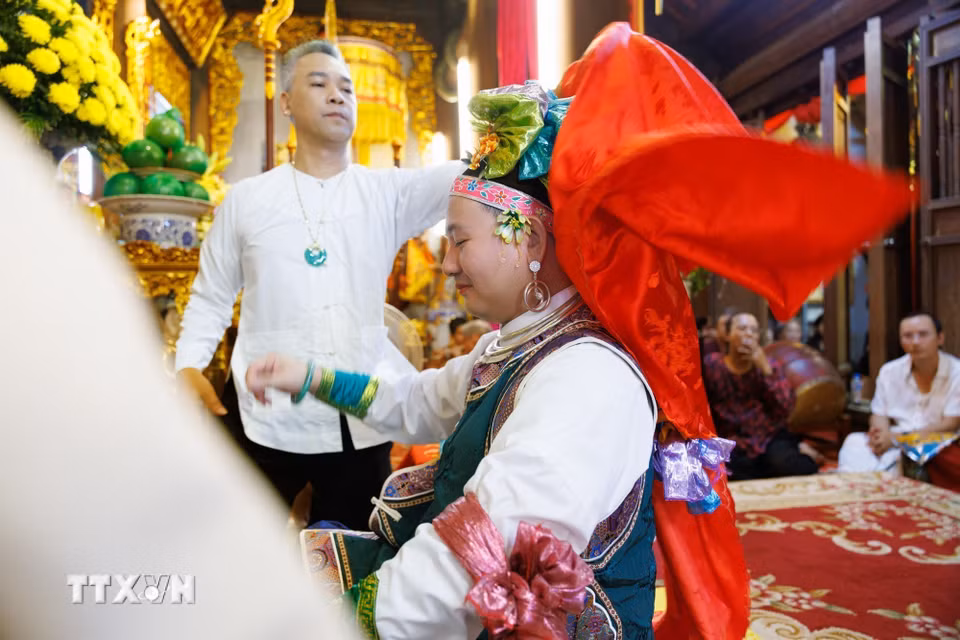 Người phụ lễ hỗ trợ thanh đồng trong quá trình thay đổi, điều chỉnh trang phục khi thực hành nghi lễ hầu đồng tại đền Hàng Vải. Bên cạnh thanh đồng và các cung văn, những người phụ lễ giữ vai trò hỗ trợ chuẩn bị khăn áo, vật phẩm và phối hợp thực hiện các công đoạn nghi lễ. Sự tham gia của nhiều thành viên thể hiện tính cộng đồng trong thực hành tín ngưỡng, nơi những kiến thức và kỹ năng truyền thống được duy trì thông qua hoạt động thực hành. (Ảnh: Phạm Tuấn Anh/TTXVN)