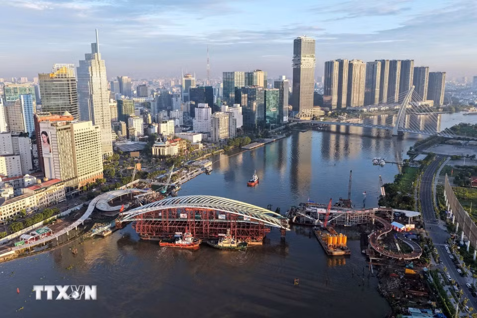 Toàn cảnh sà lan chở nhịp chính được đưa vào vị trí hợp long dự án cầu đi bộ qua sông Sài Gòn. (Ảnh: TTXVN phát)