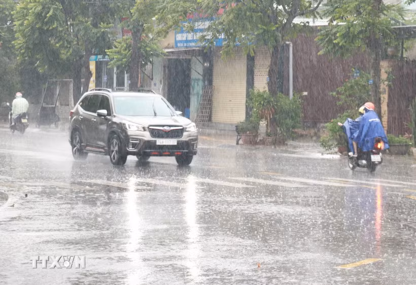 Người dân đi lại trong mưa lớn. (Ảnh: Nguyên Lý/TTXVN)