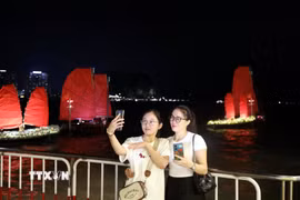 Du khách thích thú check-in cùng những chiếc thuyền buồm đỏ, một sản phẩm du lịch mới của Quảng Ninh. (Ảnh: Đức Hiếu/TTXVN)