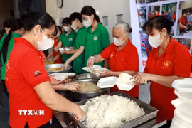 Các thành viên Hội Cơm tình nguyện (phường Thiên Trường) và học sinh trường THPT Nguyễn Khuyến (phường Nam Định) chuẩn bị các suất cơm miễn phí trao tặng người bệnh. (Ảnh: Nguyễn Lành/TTXVN)