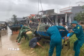 Các lực lượng hỗ trợ giúp đỡ người dân chằng chống, bảo vệ phương tiện trước khi bão vào đất liền. (Ảnh: Đoàn Hữu Trung/TTXVN)
