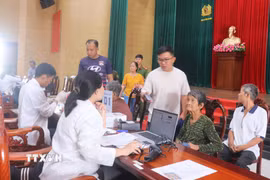 Cán bộ kỹ thuật đối chiếu thông tin và tiến hành lấy mẫu sinh phẩm ADN thân nhân liệt sỹ chưa xác định danh tính tại điểm thu nhận mẫu Công an phường Long Xuyên, tỉnh An Giang. (Ảnh: Công Mạo/TTXVN)