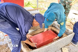 Ban Chỉ đạo về tìm kiếm, quy tập và xác định danh tính hài cốt liệt sĩ tỉnh An Giang lấy mẫu hài cốt phục vụ giám định ADN tại Nghĩa trang Liệt sỹ Tri Tôn. (Ảnh: Thanh Sang/TTXVN)
