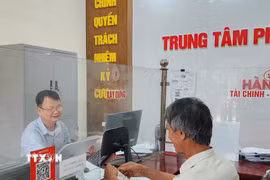 Công chức phường Mạo Khê, Quảng Ninh, hướng dẫn công dân nộp hồ sơ chứng thực lên Cổng dịch vụ công Quốc gia. (Ảnh: Thanh Vân/TTXVN)