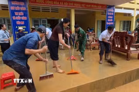 Các lực lượng chức năng và người dân khẩn trương khắc phục hậu quả mưa lũ tại các trường học. (Ảnh: TTXVN phát)