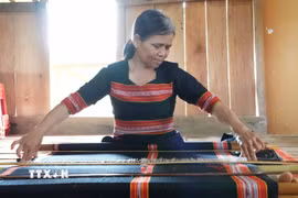 Phụ nữ Giẻ Triêng ở thôn Ri Mẹt, xã Đăk Môn, tỉnh Quảng Ngãi bên khung dệt thổ cẩm truyền thống. (Ảnh: Dư Toán/ TTXVN)