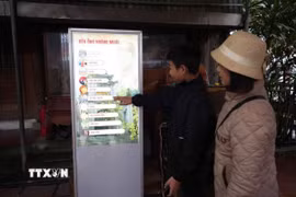Du khách sử dụng hệ thống kiosk để tìm hiểu thông tin về di tích Đền Ông Hoàng Mười. (Ảnh: Bích Huệ/TTXVN)