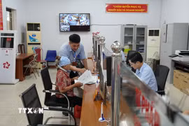 Cán bộ Trung tâm phục vụ hành chính công xã Yên Mỹ hướng dẫn hỗ trợ người già thực hiện thủ tục hành chính. (Ảnh: Mạnh Khánh/TTXVN)