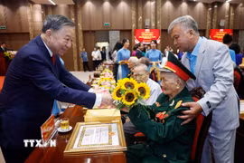 Tổng Bí thư, Chủ tịch nước Tô Lâm tặng hoa chúc mừng các đảng viên nhận Huy hiệu Đảng. (Ảnh: Thống Nhất/TTXVN)
