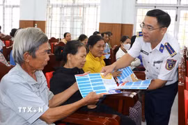 Cảnh sát biển phát tờ rơi tuyên truyền chống khai thác bất hợp pháp cho bà con ngư dân. (Ảnh: Đinh Hương/TTXVN)