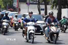 Người dân mặc đồ bảo hộ chống nắng nóng khi tham gia giao thông trên đường Hùng Vương, phường Thuận Hóa, thành phố Huế. (Ảnh: Nguyên Lý/TTXVN)