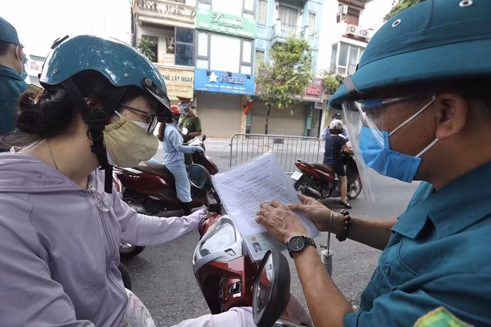 Lực lượng chức năng tại chốt kiểm soát phường Đống Mác (quận Hai Bà Trưng) nhắc nhở người dân cần hoàn thiện các mục còn thiếu đối với giấy đi đường theo quy định mới. (Ảnh: Minh Quyết/TTXVN)