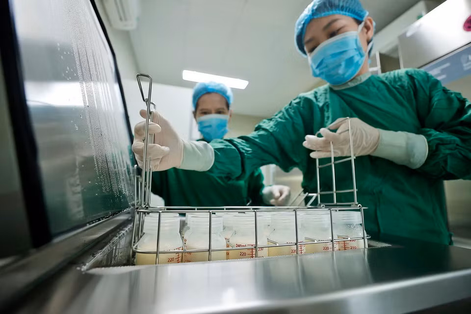 Nhân viên y tế cho sữa vào thanh trùng trước khi được chuyển tới các khoa cho bệnh nhi. (Ảnh: Minh Quyết/TTXVN)