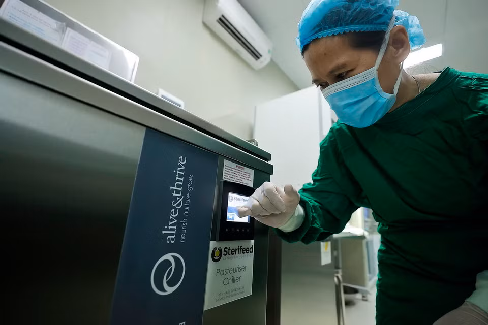 Nhân viên y tế cho sữa vào thanh trùng trước khi được chuyển tới các khoa cho bệnh nhi. (Ảnh: Minh Quyết/TTXVN)
