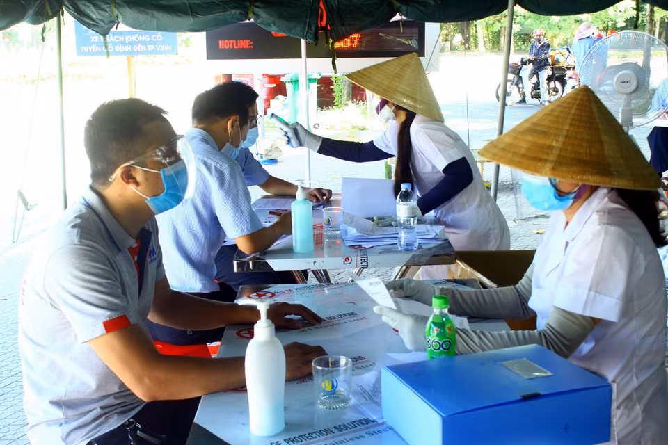  Các chủ phương tiện khai báo y tế khi đầy đủ các loại giấy tờ quy định để qua chốt kiểm soát cầu Bến Thủy. (Ảnh: Tá Chuyên/TTXVN)