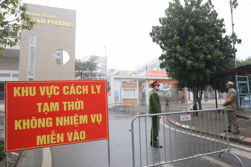 Lực lượng chức năng lập chốt tại cổng trường tiểu học Xuân Phương. (Ảnh: Minh Quyết/TTXVN)