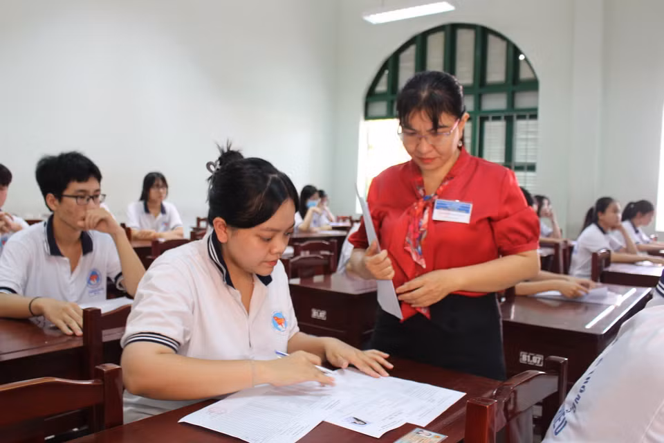 Thí sinh được cán bộ xem thi hướng dẫn điền thông tin đăng ký dự thi. (Ảnh: Hữu Chí/TTXVN)