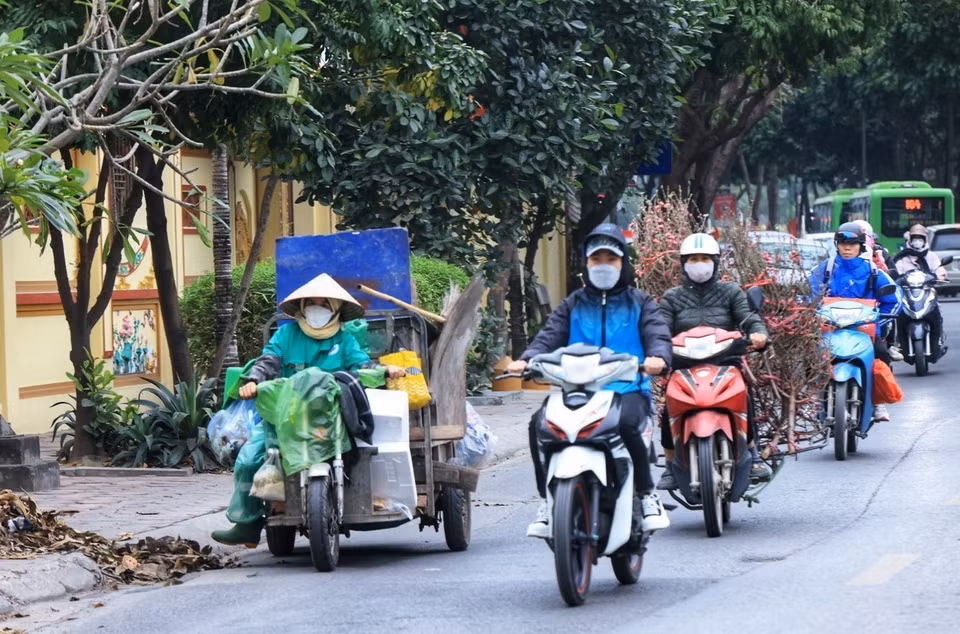 Bao người đi mua sắm Tết trong khi những công nhân Môi trường đô thị vẫn cặm cụi, miệt mài thu gom rác trên đường phố. (Ảnh: Tuấn Anh/TTXVN)