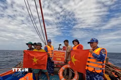 Đoàn công tác của Bộ Tư lệnh Vùng Cảnh sát biển 2 trao tặng cờ Tổ quốc, quà động viên các thuyền viên, khích lệ ngư dân yên tâm vươn khơi, bám biển. (Ảnh: TTXVN phát)