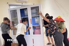 Người dân hỗ trợ di dời tài sản của trường Mầm non Xuân Mai (xã Xuân Mai, Hà Nội) lên cao tránh nước ngập. (Ảnh: TTXVN phát)