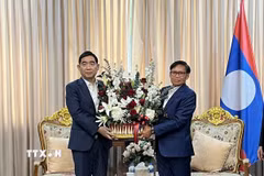 Đại sứ Phạm Việt Hùng (trái) tặng lãng hoa tới Đại sứ Lào Sisavath Inphachanh chúc mừng 50 năm Quốc khánh Lào. (Ảnh: Đỗ Sinh/TTXVN)