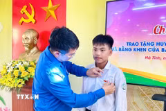 Trao tặng Huy hiệu "Tuổi trẻ dũng cảm" cho em Chu Văn Tuấn Vũ. (Ảnh: TTXVN phát)