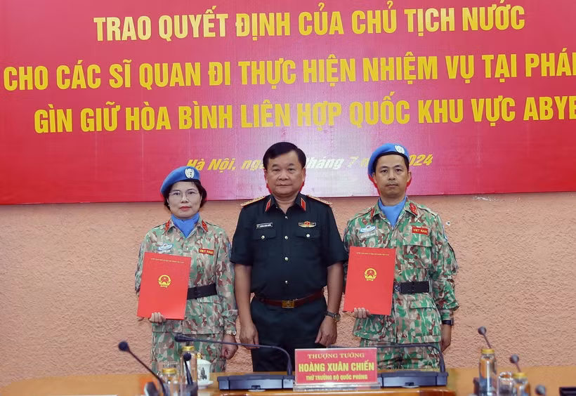 Thượng tướng Hoàng Xuân Chiến, Thứ trưởng Quốc phòng, Tổ trưởng Tổ Công tác liên ngành, Trưởng Ban Chỉ đạo Bộ Quốc phòng về tham gia hoạt động gìn giữ hòa bình Liên hợp quốc trao Quyết định của Chủ tịch nước cho thượng tá Nguyễn Thị Liên và trung tá Nguyễn Đức Doanh. (Ảnh: Trọng Đức/TTXVN)