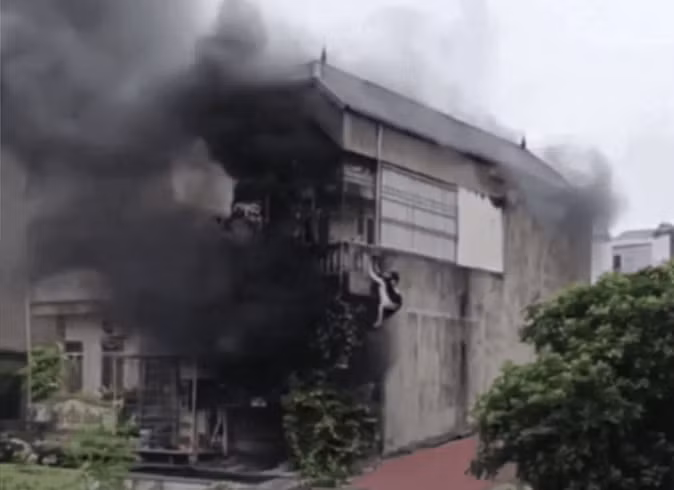 Hình ảnh anh Bằng cõng 2 cô gái leo tường thoát khỏi vụ cháy. (Ảnh cắt từ clip).