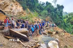 Người dân dùng xà beng, búa tạ phá nhỏ những tảng đá lớn tại điểm sạt lở trước khi kích nâng lên thanh trượt để dịch chuyển sang mép vực, tạo lối mở qua điểm sạt lở. (Ảnh: TTXVN phát)