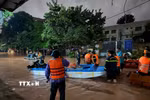 Lực lượng chức năng dùng thuyền di dời các hộ dân về nơi an toàn. (Ảnh: Tiến Vĩnh/TTXVN)