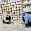 Những người thợ gốm Bát Tràng với những sản phẩm được làm tại xưởng gốm Bát Tràng (Hà Nội). (Ảnh: Tuyết Mai/TTXVN)