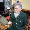 Ông Nguyễn Thế Tám nâng niu chiến tích tịch thu được của quân địch trong thời gian tham gia giải phóng Sài Gòn. (Ảnh: Công Luật/TTXVN)