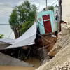 Một phần căn nhà và khu vực chứa vật liệu xây dựng bị sạt lở, sụp xuống sông sau sự cố xảy ra vào đêm 27/7/2026. (nh: TTXVN phát)