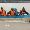 Các lực lượng chức năng sử dụng cano tiếp cận các điểm xung yếu ngập lụt, ứng cứu các hộ dân bị cô lập. (Ảnh: Nguyễn Thành/TTXVN)