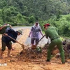 Cán bộ, chiến sỹ công an các xã của tỉnh Tuyên Quang cùng người dân san gạt đất đá, khơi thông tuyến đường bị sạt lở do mưa lũ. (Ảnh: TTXVN phát)